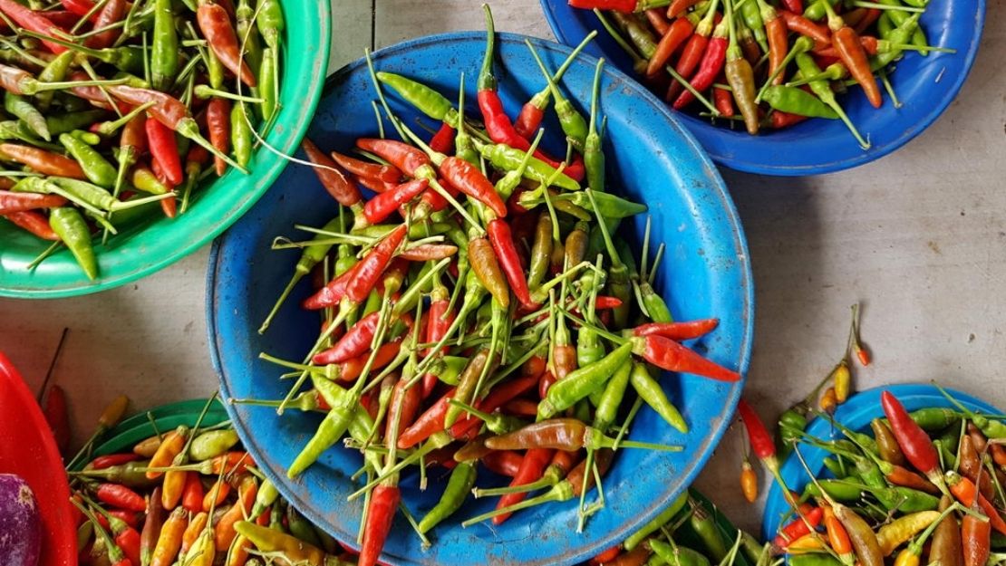 Overhead view of chili peppers piled in bowls, creating a vibrant, rustic market display.