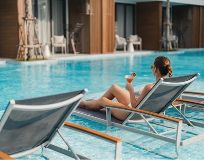 A woman lounging by a pool while holding a cocktail.