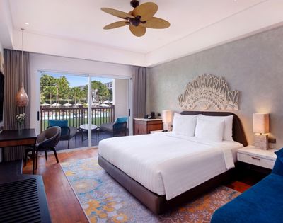 A modern hotel room featuring a large bed, wooden furniture, and a view of a pool through sliding glass doors.