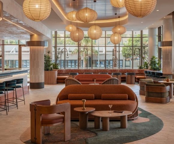 Interior view of a modern lounge area with an eye-catching bar, comfortable seating arrangements in warm, earthy tones, and large windows offering a glimpse of the outdoors.