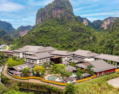 Aerial view of a modern resort surrounded by lush greenery and mountains.