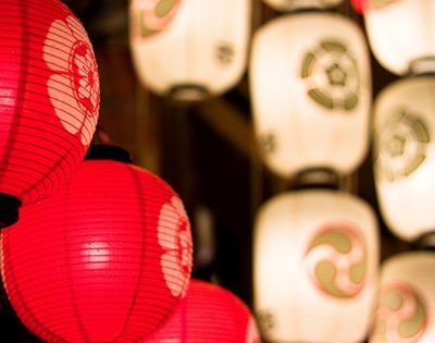 Close-up of glowing red and white paper lanterns with Japanese-style designs, creating a warm, festive atmosphere.
