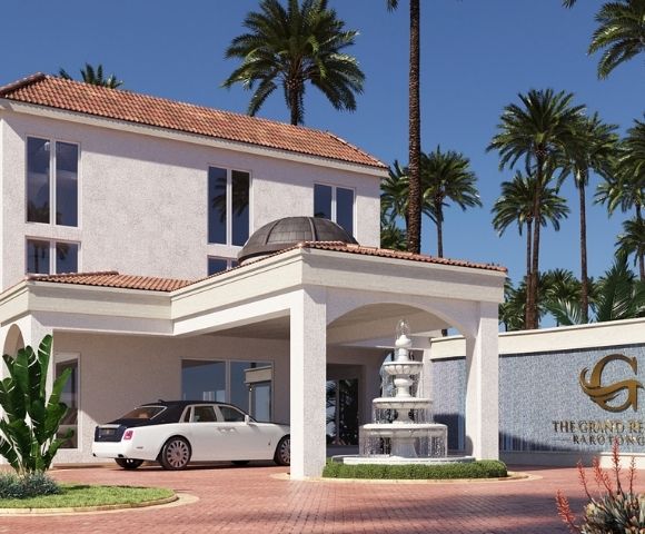 A white luxury sedan is parked at the entrance of a modern resort with palm trees in the background.