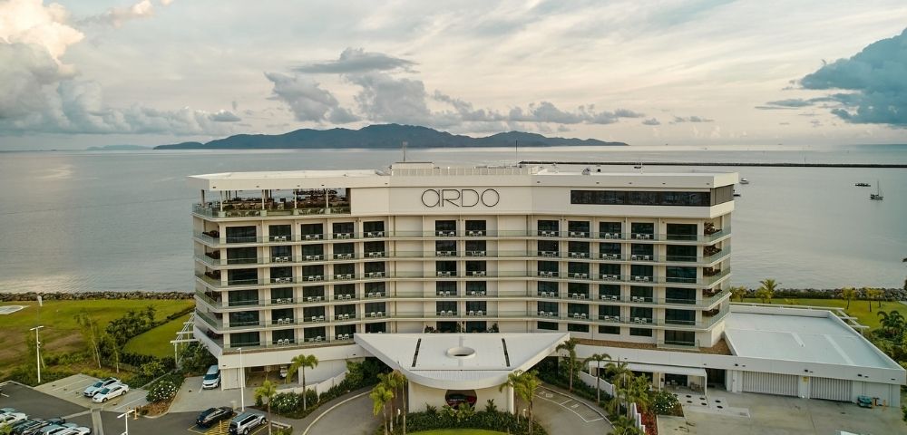 Aerial view of a modern, multi-story hotel building with balconies, labeled 