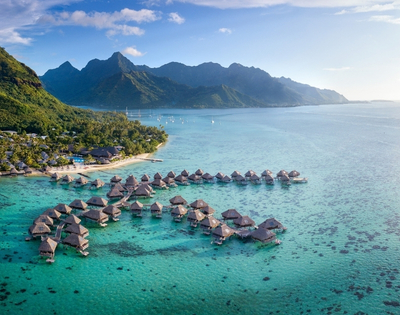 Aerial view of luxurious overwater bungalows in Bora Bora, surrounded by turquoise waters and lush greenery.