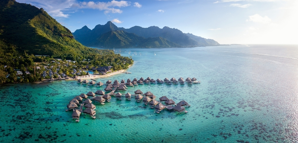 Aerial view of luxurious overwater bungalows in Bora Bora, surrounded by turquoise waters and lush greenery.