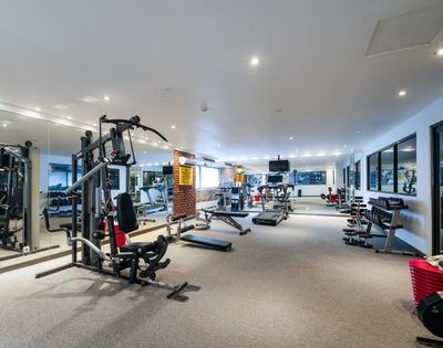 A well-equipped gym with cardio machines, weight machines, dumbbells, and benches.