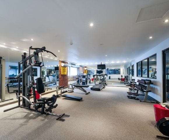 A well-equipped gym with cardio machines, weight machines, dumbbells, and benches.