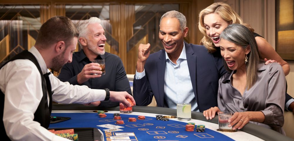 A diverse group of people express excitement and joy around a casino gaming table during a game.