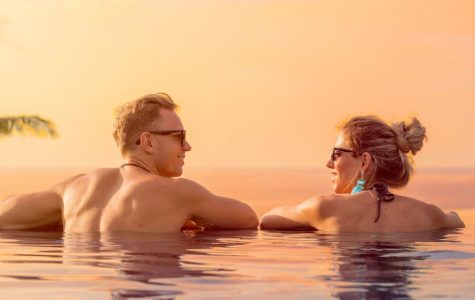 Couple relaxing in a swimming pool at sunset, enjoying a peaceful moment together.