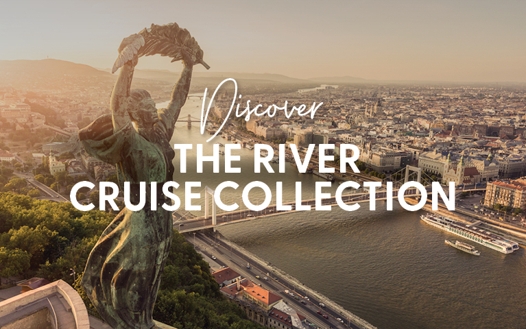 Statue overlooking a river cruise ship on a wide river beside a bustling city at sunset. Text overlay: 