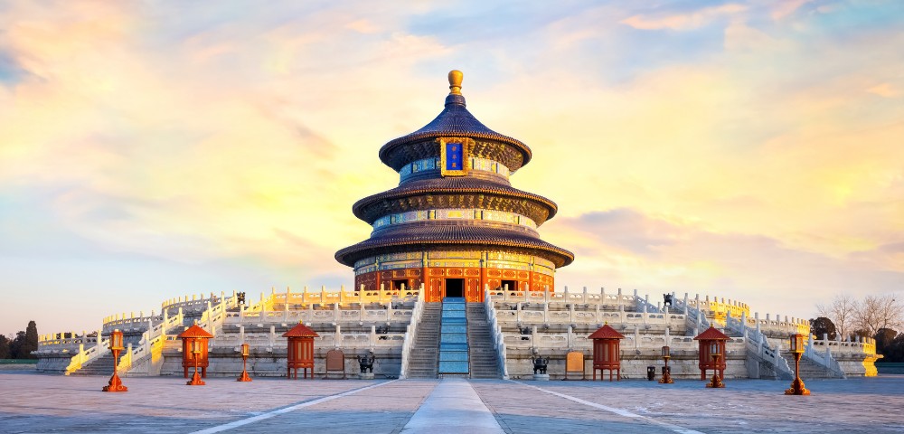 A majestic temple with a circular, multi-tiered roof stands under a vibrant sunset sky. The scene conveys grandeur, tranquility, and cultural richness.