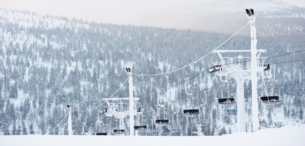 A ski lift ascends a snowy mountain, surrounded by a pristine winter landscape.