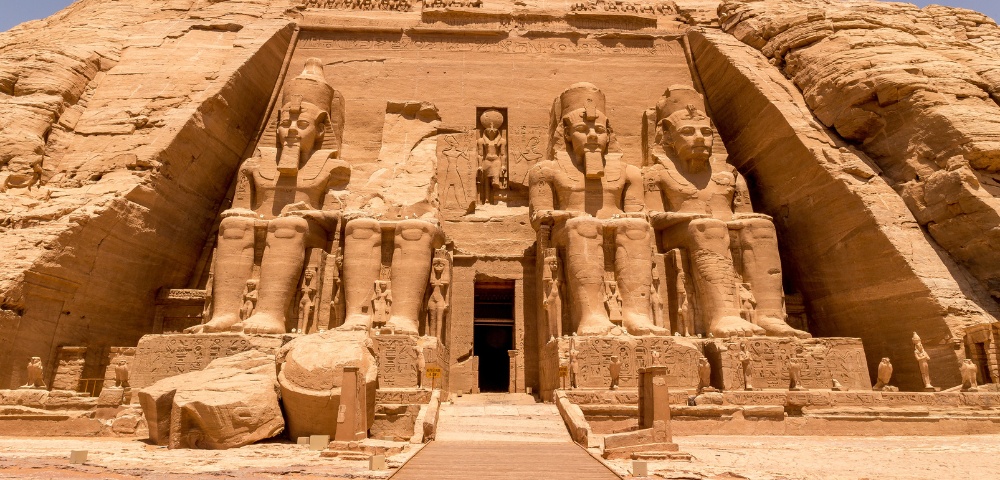 The Great Temple of Abu Simbel in Egypt, featuring four colossal statues of Pharaoh Ramses II carved into a sandstone cliff under a clear sky.