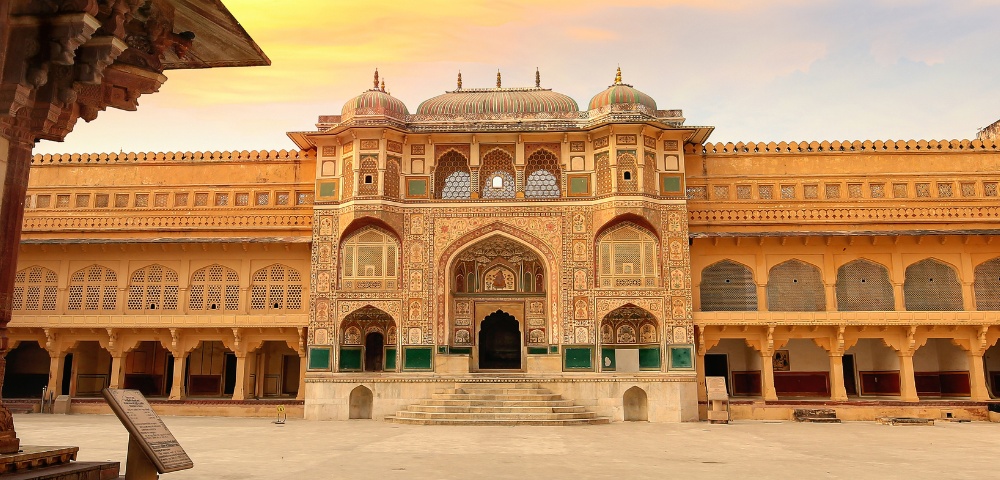Majestic palace facade with intricate arches and domes under a golden sky, evoking grandeur and historical elegance. Warm tones dominate the scene.