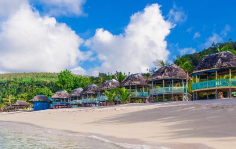 Aerial view of a tropical island resort surrounded by clear blue water and lush greenery.